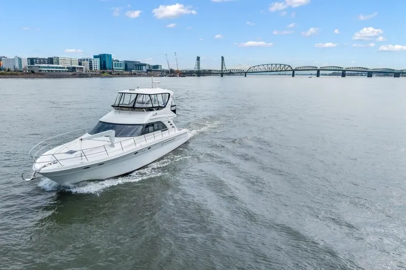 Slide: The Image of 1999 Sea Ray 560 Sedan Bridge cruising on a river with cityscape and bridge in background. - 10