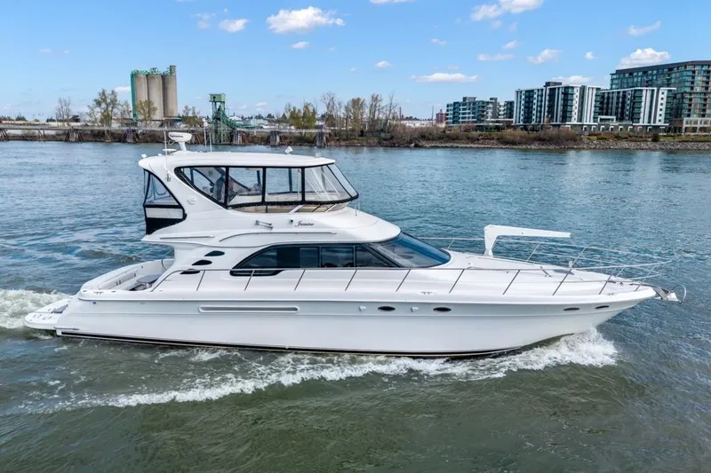 Slide: The Image of 1999 Sea Ray 560 Sedan Bridge yacht cruising on a river with cityscape background. - 14