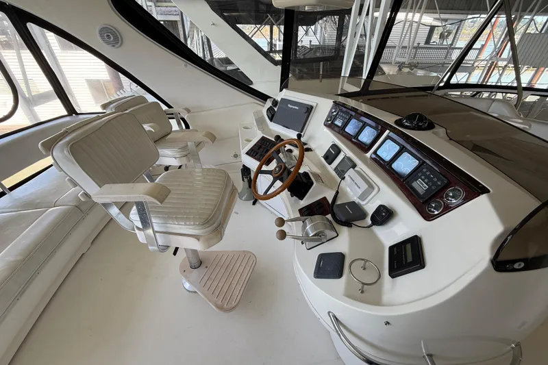 Slide: The Image of 1999 Sea Ray 560 Sedan Bridge helm with dual seats, steering wheel, and navigation instruments. - 18