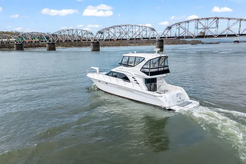Slide: The Image of 1999 Sea Ray 560 Sedan Bridge yacht cruising near a bridge on a sunny day. - 2