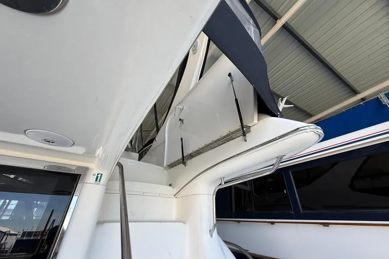 Slide: The Image of 1999 Sea Ray 560 Sedan Bridge yacht under a covered dock, showcasing sleek design elements. - 23
