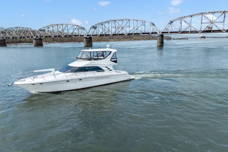 Slide: The Image of 1999 Sea Ray 560 Sedan Bridge yacht cruising near a bridge on a sunny day. - 3