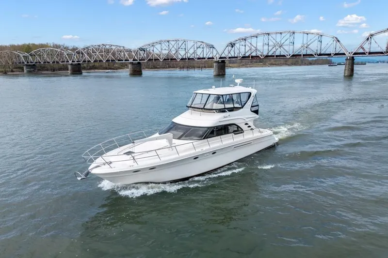 Slide: The Image of 1999 Sea Ray 560 Sedan Bridge yacht cruising under a bridge on a sunny day. - 4