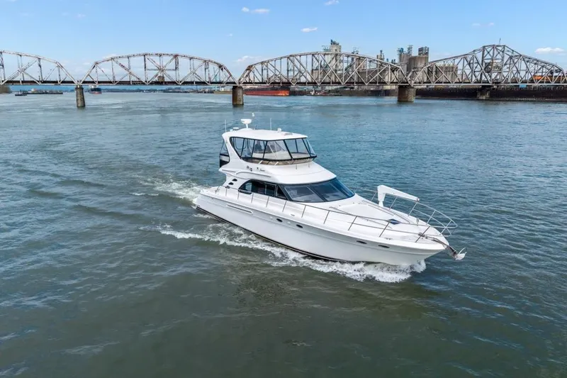 Slide: The Image of 1999 Sea Ray 560 Sedan Bridge yacht cruising near a bridge on a sunny day. - 5