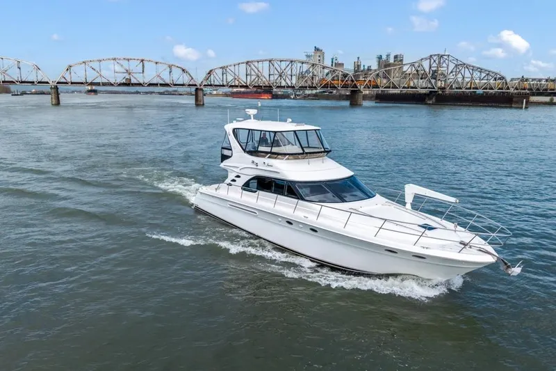 Slide: The Image of 1999 Sea Ray 560 Sedan Bridge yacht cruising near a bridge on a sunny day. - 6