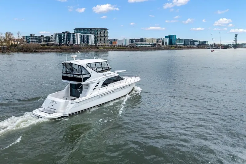 Slide: The Image of 1999 Sea Ray 560 Sedan Bridge yacht cruising on a river with cityscape background. - 7