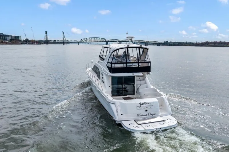 Slide: The Image of 1999 Sea Ray 560 Sedan Bridge yacht cruising on a river with a bridge in the background. - 9