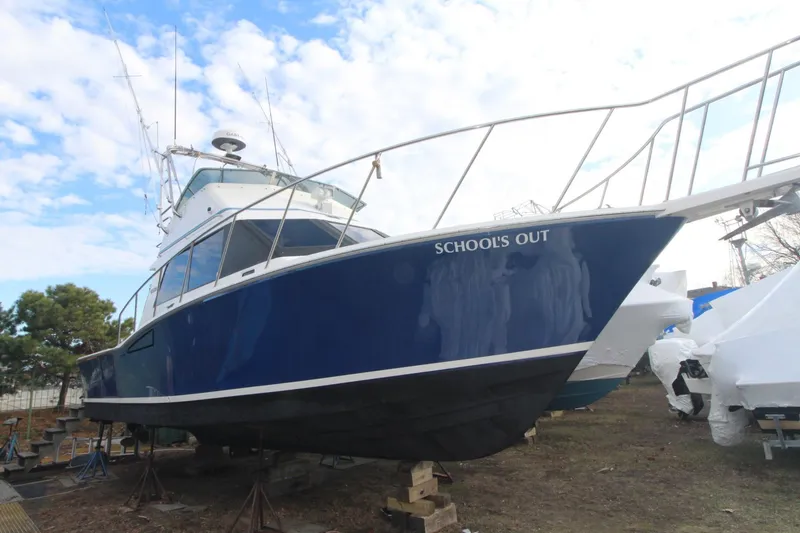 The Image of 1999 Cabo 35 Flybridge boat named "School's Out" on dry dock, blue hull. - 1