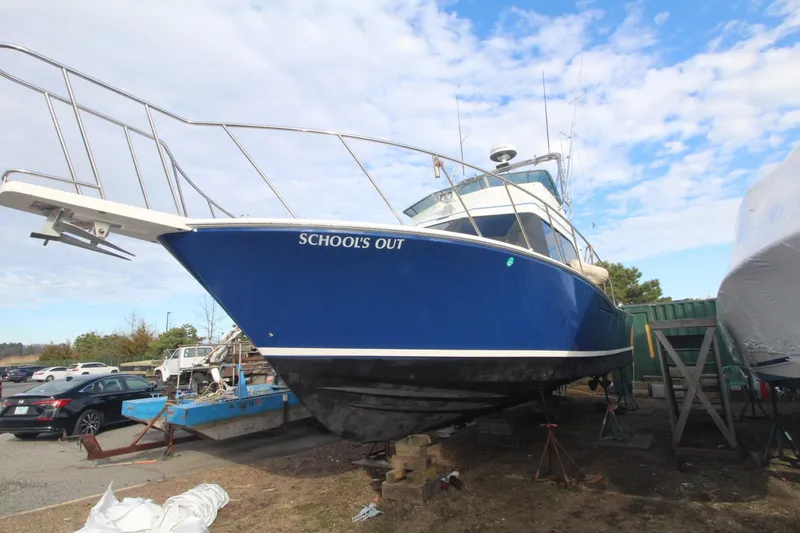 Slide: The Image of 1999 Cabo 35 Flybridge boat named "School's Out" on dry dock under blue sky. - 11