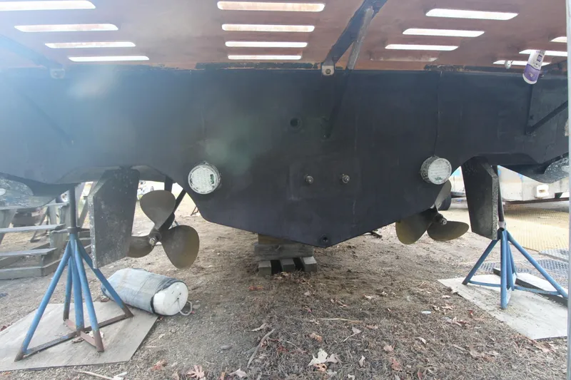 Slide: The Image of Underneath view of a 1999 Cabo 35 Flybridge boat on stands, showing propellers and hull. - 9
