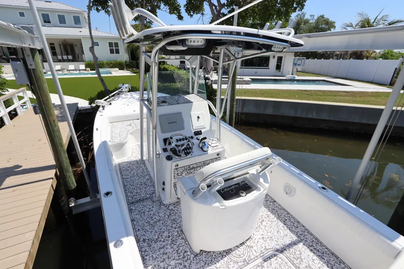 Slide: The Image of 2014 Canyon Bay 2400 boat docked near a waterfront home, featuring a sleek console design. - 11