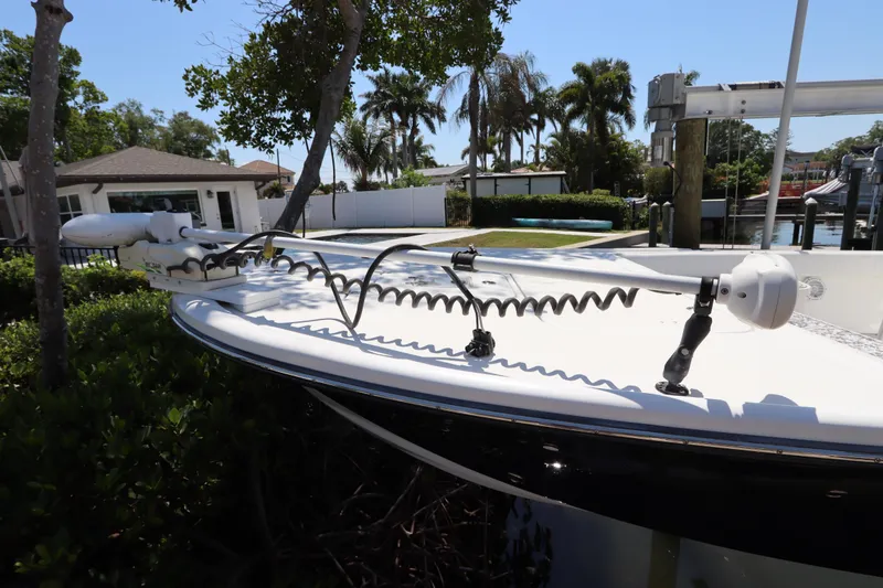 Slide: The Image of 2014 Canyon Bay 2400 boat with trolling motor, docked near lush greenery and waterfront homes. - 3