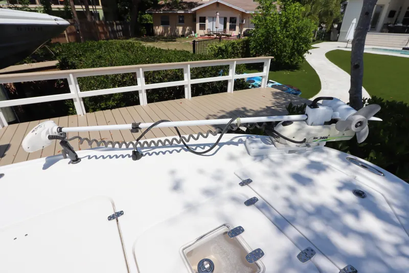 Slide: The Image of 2014 Canyon Bay 2400 boat with trolling motor on deck, docked near lush greenery. - 4