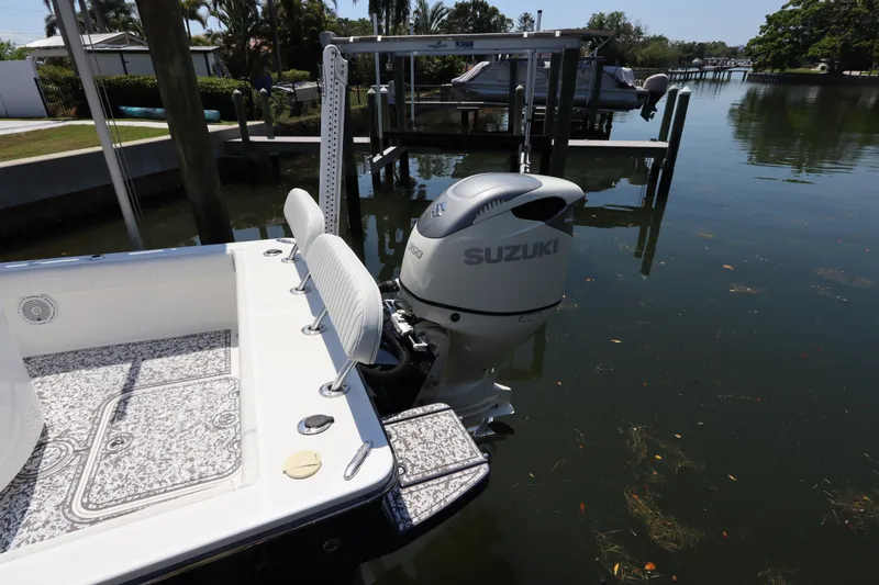 Slide: The Image of Canyon Bay 2400 boat with Suzuki outboard motor docked in a serene waterfront setting. - 5
