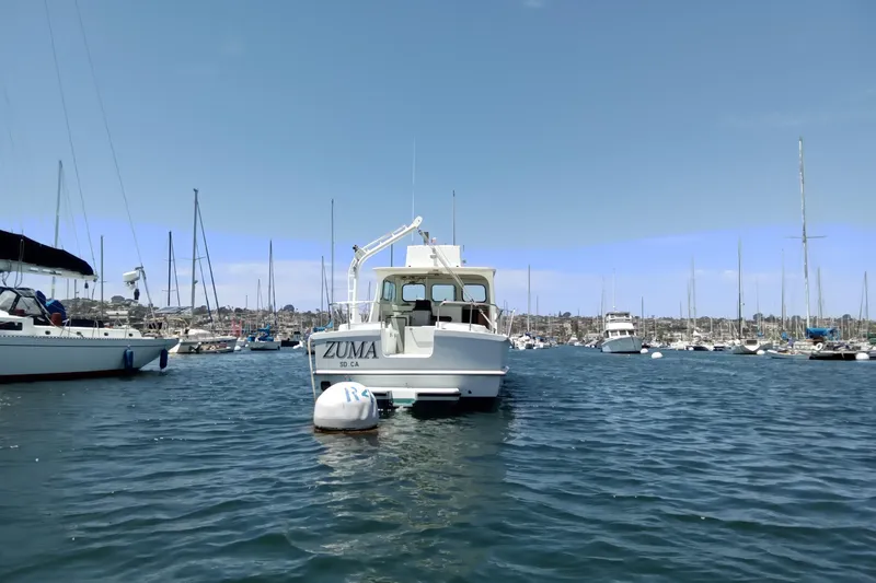 Slide: The Image of A 1972 Uniflight 40 boat named "Zuma" moored in a bustling marina. - 2