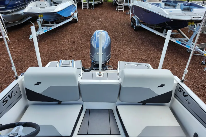 Slide: The Image of 2026 Starcraft SV 16 OB boat interior with motor, surrounded by other boats on trailers. - 17