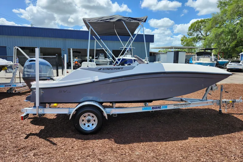 Slide: The Image of 2026 Starcraft SV 16 OB boat on trailer, parked outdoors under a sunny sky. - 7