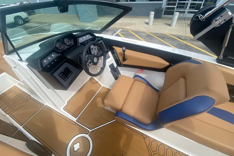 Slide: The Image of 2023 MasterCraft NXT21 boat interior with tan and blue seating, modern dashboard, and steering wheel. - 21
