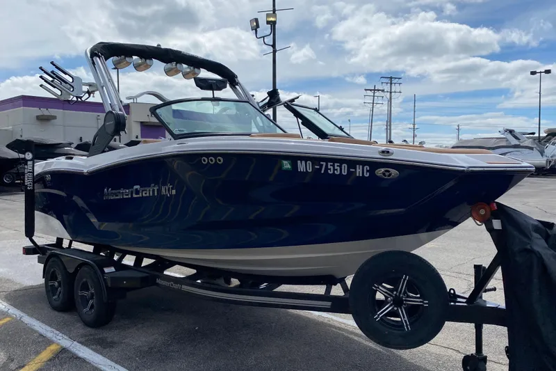 Slide: The Image of 2023 MasterCraft NXT21 boat on trailer, parked outdoors under cloudy sky. - 8