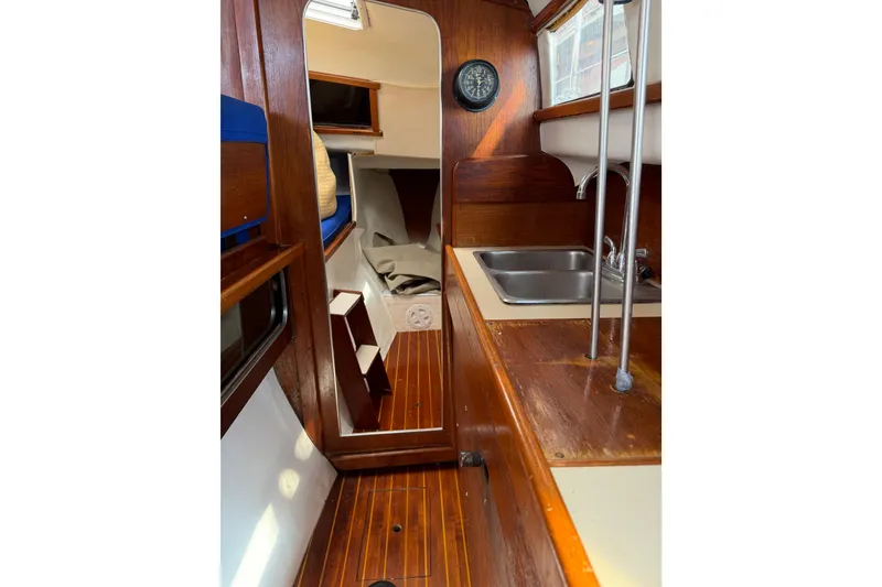 Slide: The Image of Interior of 1989 Gemini 3000 sailboat with wooden finish and compact kitchen area. - 13