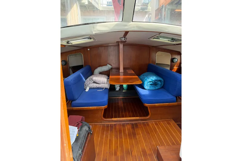 Slide: The Image of Interior of a 1989 Gemini 3000 sailboat with blue cushioned seating and wooden finishes. - 6