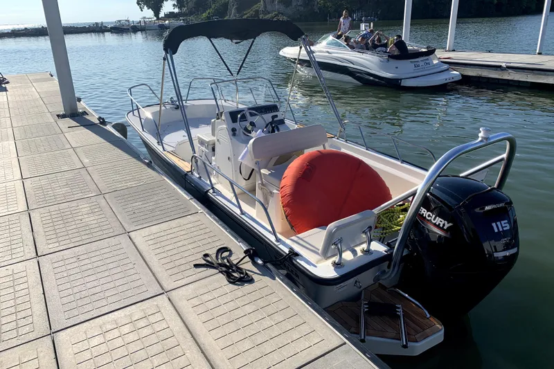 Slide: The Image of 2020 Boston Whaler 170 Montauk docked, featuring Mercury 115 engine and canopy. - 2