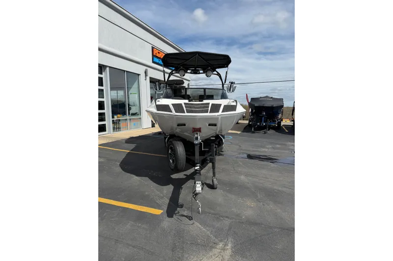 Slide: The Image of 2025 Moomba Makai boat on trailer outside dealership under blue sky. - 8