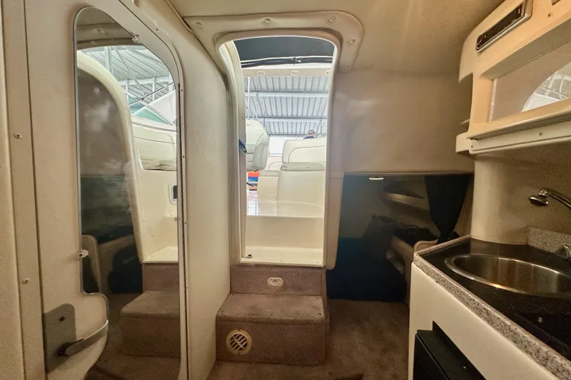 Slide: The Image of Interior view of 2001 Rinker Fiesta Vee 270 boat, featuring compact kitchenette and seating area. - 12