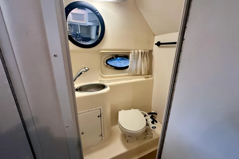 Slide: The Image of 2001 Rinker Fiesta Vee 270 boat bathroom with sink, toilet, and porthole window. - 9