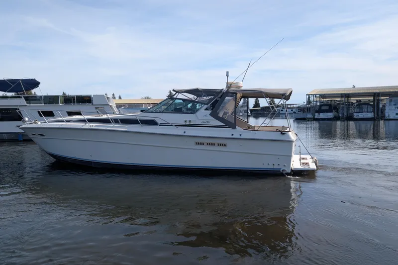 The Image of 1987 Sea Ray 390 Express Cruiser on calm water near marina. - 0