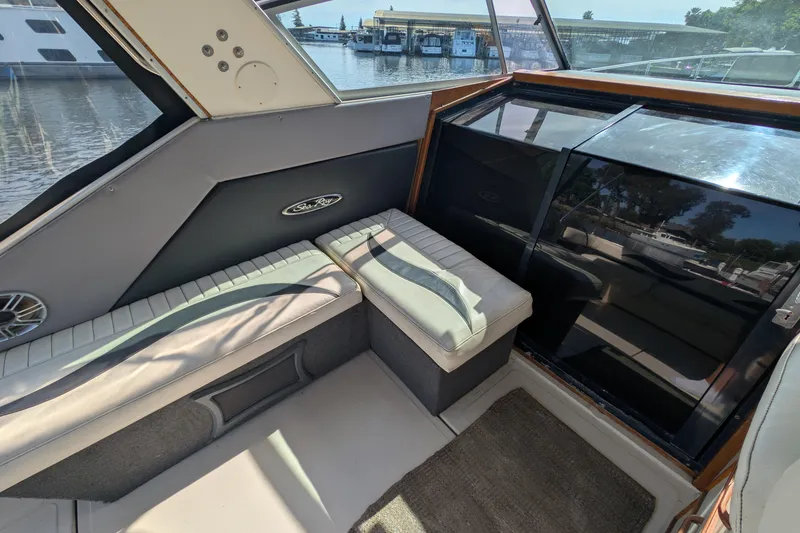 Slide: The Image of Interior view of 1987 Sea Ray 390 Express Cruiser with cushioned seating and marina backdrop. - 13