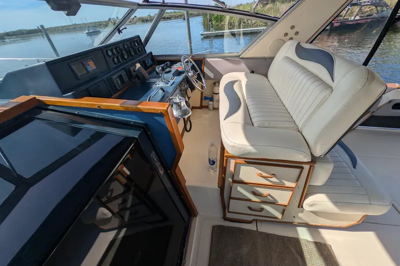 Slide: The Image of 1987 Sea Ray 390 Express Cruiser cockpit with dual seats and control panel, docked by water. - 14