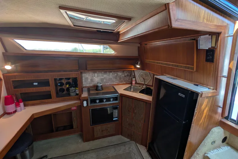 Slide: The Image of Interior of 1987 Sea Ray 390 Express Cruiser with kitchen amenities and wooden cabinetry. - 18