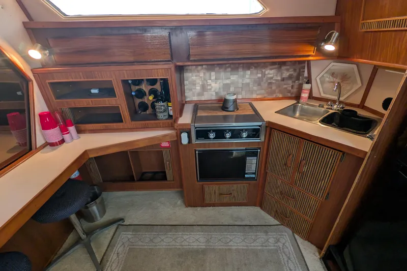 Slide: The Image of 1987 Sea Ray 390 Express Cruiser kitchen with stove, sink, and wooden cabinetry. - 20