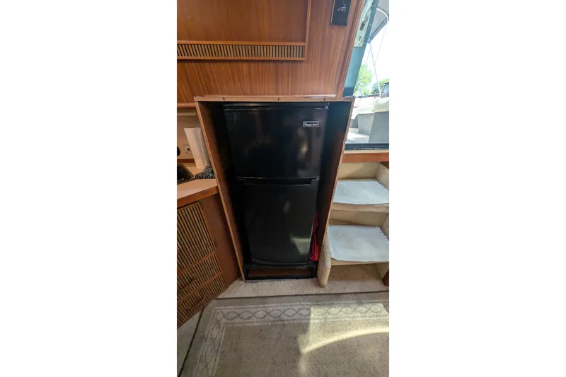 Slide: The Image of Black fridge inside 1987 Sea Ray 390 Express Cruiser cabin, near carpeted stairs. - 24