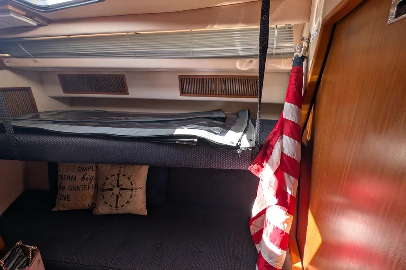 Slide: The Image of Interior of 1987 Sea Ray 390 Express Cruiser with bunk, flag, and decorative pillows. - 31