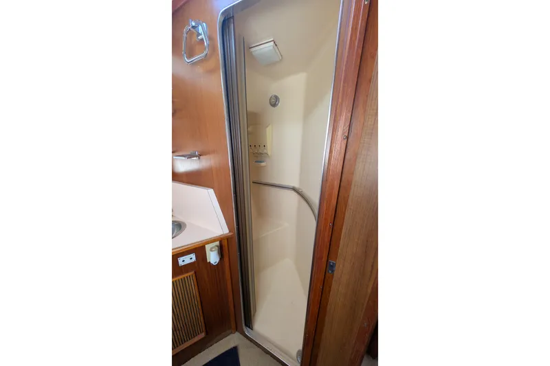 Slide: The Image of Shower area inside 1987 Sea Ray 390 Express Cruiser, featuring wood paneling and compact design. - 34