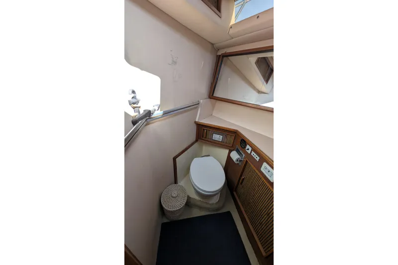 Slide: The Image of 1987 Sea Ray 390 Express Cruiser bathroom interior with toilet, mirror, and wooden cabinetry. - 35