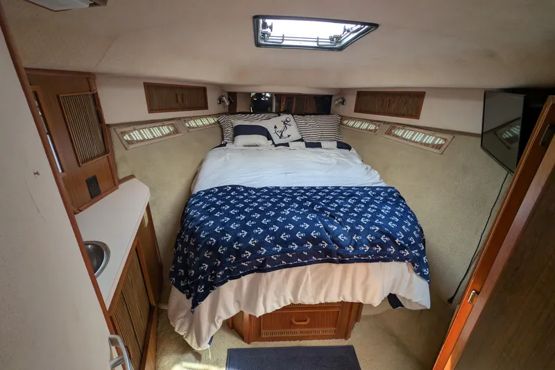 Slide: The Image of Cozy cabin interior of 1987 Sea Ray 390 Express Cruiser with nautical-themed bedding. - 36