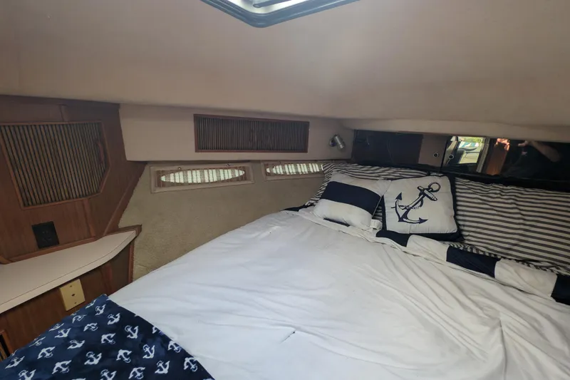 Slide: The Image of Cozy cabin interior of 1987 Sea Ray 390 Express Cruiser with nautical-themed bedding. - 38