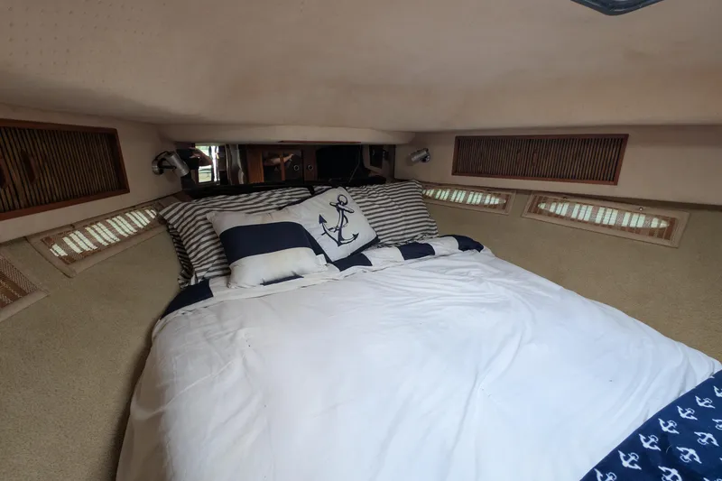 Slide: The Image of Cozy cabin interior of 1987 Sea Ray 390 Express Cruiser with nautical-themed bedding. - 39