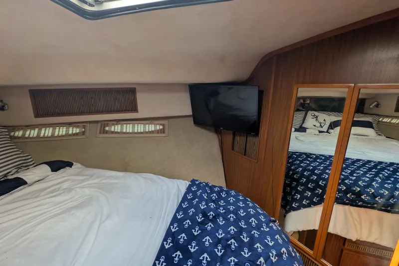 Slide: The Image of 1987 Sea Ray 390 Express Cruiser cabin with bed, TV, and nautical decor. - 40
