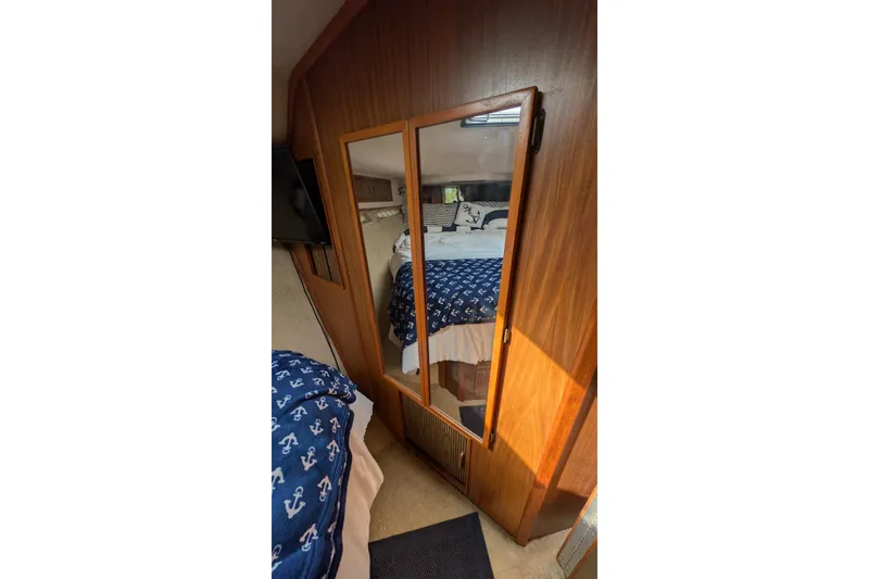 Slide: The Image of Interior of 1987 Sea Ray 390 Express Cruiser with mirrored closet and nautical-themed bedding. - 41