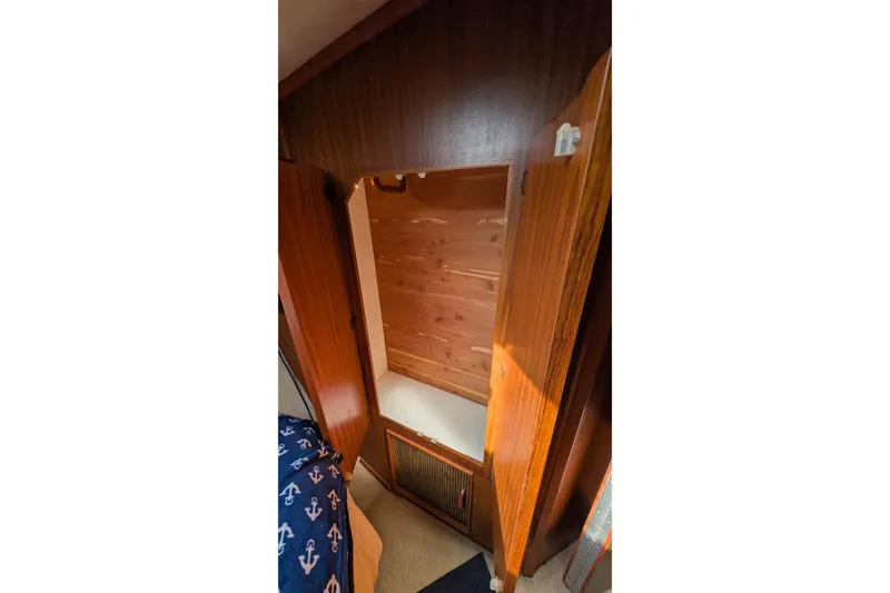 Slide: The Image of Interior of 1987 Sea Ray 390 Express Cruiser, featuring wooden cabinetry and nautical-themed bedding. - 42