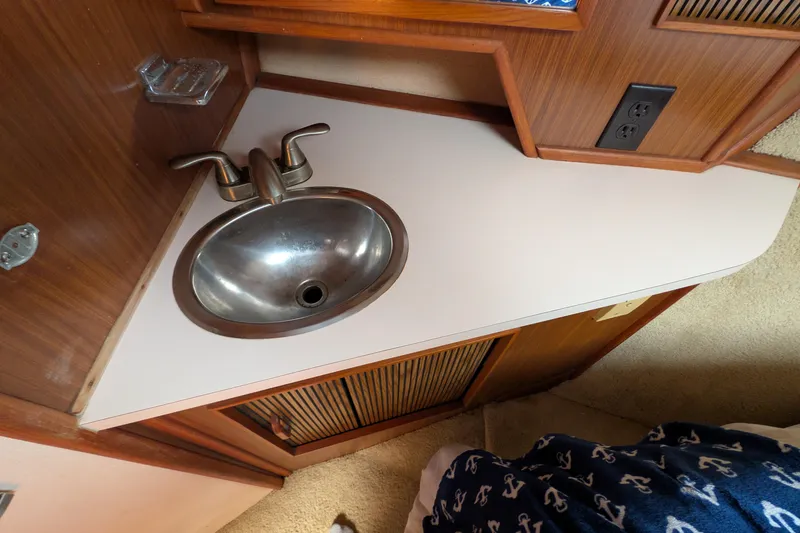 Slide: The Image of 1987 Sea Ray 390 Express Cruiser bathroom sink with wooden cabinetry and nautical-themed decor. - 43