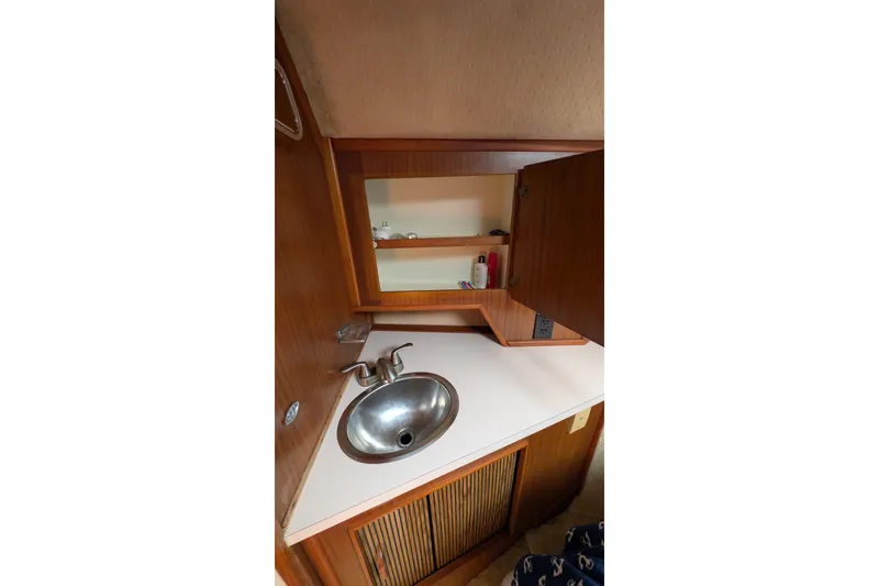 Slide: The Image of 1987 Sea Ray 390 Express Cruiser bathroom sink with wooden cabinetry and open storage. - 44