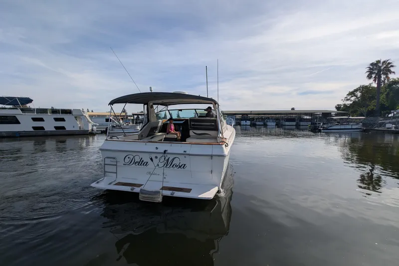 Slide: The Image of 1987 Sea Ray 390 Express Cruiser docked in a marina, calm water, clear sky. - 54