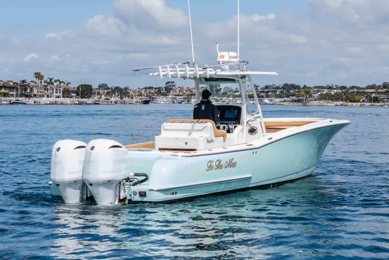 Slide: The Image of 2015 Mag Bay 33 CC boat cruising on a calm blue sea near a coastal town. - 10