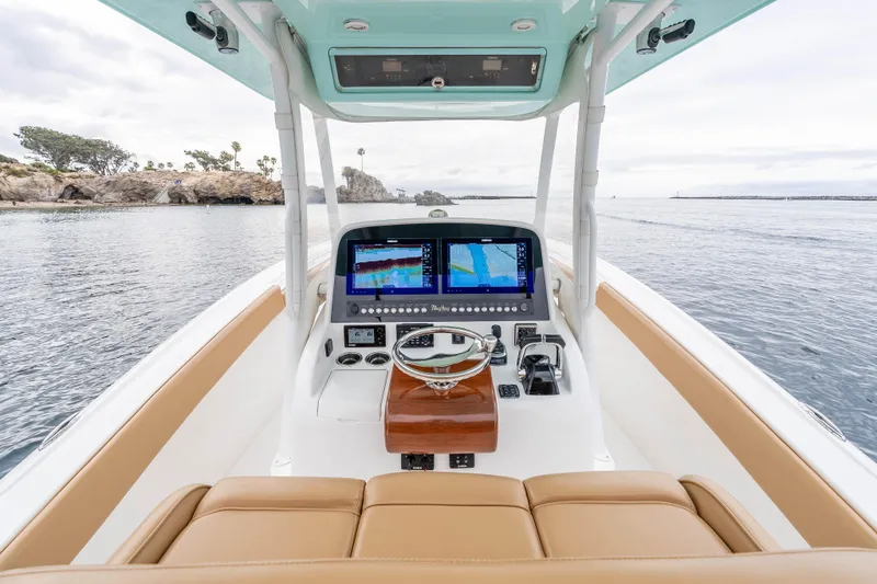 Slide: The Image of 2015 Mag Bay 33 CC boat helm with dual navigation screens, steering wheel, and ocean view. - 13