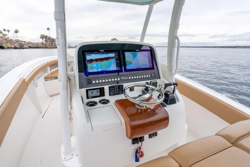Slide: The Image of 2015 Mag Bay 33 CC boat cockpit with navigation screens and steering wheel. - 15